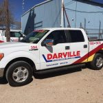 Pickup truck with "Davenport" branding and contact number, parked outside The Darville Company's service facility.